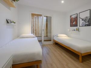 Apartment Ginesta by Interhome في لا مولينا: سريرين في غرفة بجدران بيضاء وأرضية خشبية