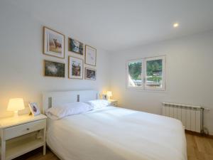 a white bedroom with a white bed and a window at Apartment Ginesta by Interhome in La Molina