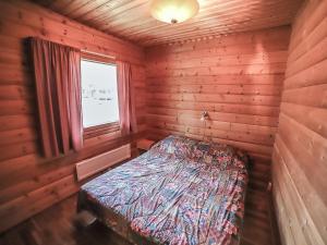ein Schlafzimmer mit einem Bett in einer Holzhütte in der Unterkunft Holiday Home Pihatupa 1 by Interhome in Kuusamo + 4 Fotos