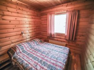 ein Bett in einem Holzzimmer mit Fenster in der Unterkunft Holiday Home Pihatupa 1 by Interhome in Kuusamo