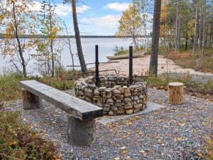 un banco de madera junto a una hoguera junto a un lago en Holiday Home Villa korpi by Interhome, 