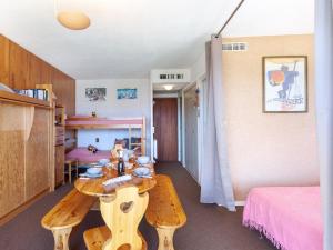 Pokój z drewnianym stołem i łóżkiem w obiekcie Apartment Mont Charvin by Interhome w mieście La Toussuire