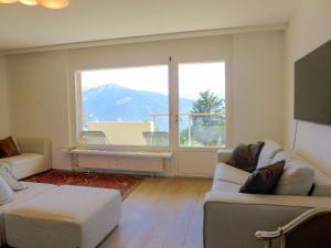 a living room with a couch and a large window at Apartment Clair-Azur-3 by Interhome in Crans-Montana