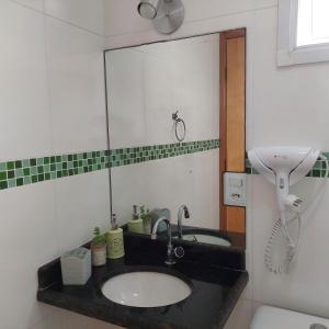 une salle de bain avec un lavabo et un miroir dans l'établissement Amor e aconchego beira mar e ar condicionado, à Praia Grande 20 autres photos