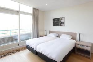 a bedroom with a bed and a large window at Hello Zeeland - Appartement Loverendale 31 in Domburg