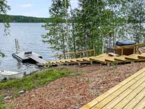 a wooden dock with a boat on the water at Holiday Home Hot pool cottage kesäranta by Interhome in Ihamaniemi