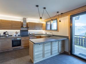 a kitchen with wooden cabinets and a large window at Holiday Home L'Adret by Interhome in Saint-Gervais-les-Bains