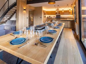 a long table in a kitchen with blue plates and silverware at Holiday Home L'Adret by Interhome in Saint-Gervais-les-Bains