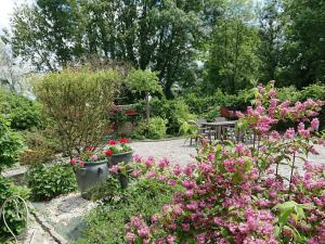 un giardino con fiori rosa e un tavolo da picnic di Holiday Home Le Camélia by Interhome a Beuvron-en-Auge