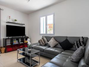 a living room with a leather couch and a flat screen tv at Holiday Home Villa Les Treilles by Interhome in Le Racou