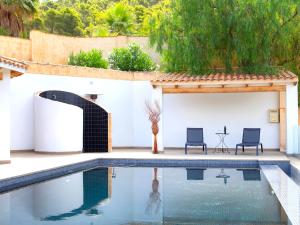 una piscina en el patio trasero de una casa con 2 sillas en Villa Mucho by Interhome, en Finestrat