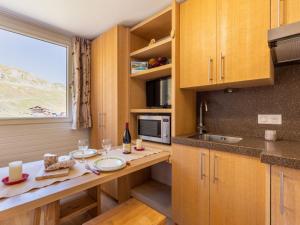 a kitchen with wooden cabinets and a table and a window at Studio Palafour - Le Lac-5 by Interhome in Tignes