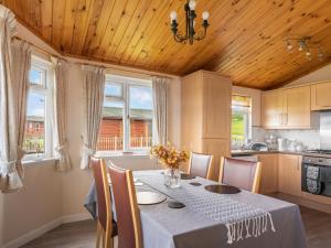 uma sala de jantar com uma mesa e algumas janelas em Chalet Loch Side Lodge 5 by Interhome em Kinross