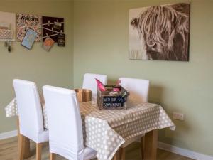a table with white chairs and a table with a basket on it at Holiday Home An Caladh by Interhome in Harlosh