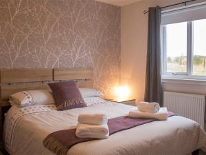 a bedroom with a bed with towels on it at Holiday Home An Caladh by Interhome in Harlosh