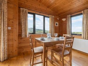 ein Esszimmer mit einem Tisch, Stühlen und Fenstern in der Unterkunft Chalet Loch Side Lodge 8 by Interhome in Kinross