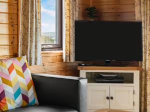 ein Wohnzimmer mit einem TV und einem Sofa in der Unterkunft Chalet Loch Side Lodge 8 by Interhome in Kinross