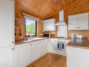 a kitchen with white cabinets and a wooden ceiling at Chalet Loch Side Lodge 8 by Interhome in Kinross +9 photos