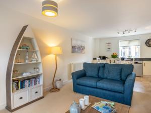 een woonkamer met een blauwe bank en een boekenplank bij Apartment Stones Throw by Interhome in St Austell