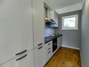 uma cozinha com armários brancos, um lavatório e uma janela em Apartment Ronscione Bellavista by Interhome em San Cassiano