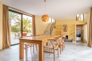 a dining room with a wooden table and chairs at Villa sa Palmera in Ses Salines