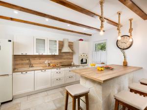 a kitchen with white cabinets and a wooden counter top at Holiday Home Paesana Heritage House by Interhome in Vrbnik