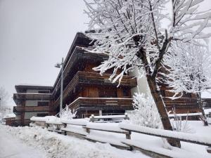 a building covered in snow next to a tree at Apartment Torrita di Canazei by Interhome in Alba di Canazei