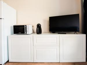 uma televisão em cima de um armário branco com um micro-ondas em Apartment Trilo Garden by Interhome em Marina di Bibbona