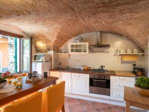a kitchen with white cabinets and a stone wall at Apartment Ca du Ponte by Interhome in Dolcedo