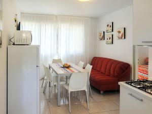 a kitchen and living room with a table and a red couch at Apartment Primula by Interhome in Bibione