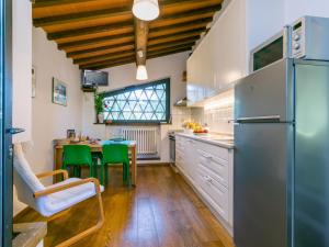 uma cozinha com um frigorífico e uma mesa com cadeiras verdes em Apartment L'Angolo di Uzzano by Interhome em Greve in Chianti