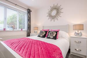 a bedroom with a pink bed with pink pillows at 4 Eureka Waldringfield Air Manage Suffolk in Woodbridge