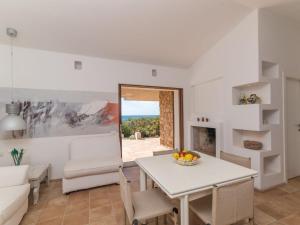 Sala de estar blanca con mesa y silla en Holiday Home Morellino by Interhome, en Aglientu