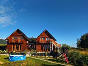 una grande casa in legno con una cabina blu davanti di Siedlisko na Jastrząbce a Lipowa