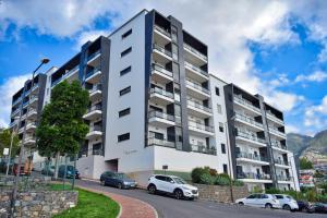 a white apartment building with cars parked in front of it at Design Gardens, a Home in Madeira in Funchal