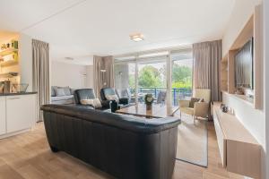 uma sala de estar com um grande sofá de couro preto em Hello Zeeland - Appartement Loverendale 10 em Domburg