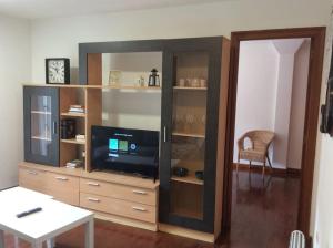 a living room with a tv in a wooden entertainment center at HyP - A Casa do Correo Vello 1ºA / O TEMPO in Pontevedra