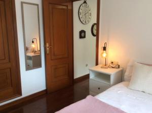 a bedroom with a bed and a clock on the wall at HyP - A Casa do Correo Vello 1ºA / O TEMPO in Pontevedra