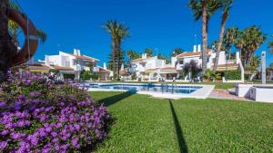 a resort with a swimming pool and palm trees and purple flowers at Casa Aisea 2 Torre del Mar by Ruralidays in Torre del Mar