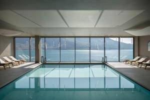 einen Pool mit Stühlen und Blick auf das Wasser in der Unterkunft EALA My Lakeside Dream - Adults Friendly in Limone sul Garda