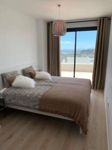 sypialnia z łóżkiem i dużym oknem w obiekcie Prachtig appartement met zeezicht in Estepona Costa del Sol w mieście Estepona