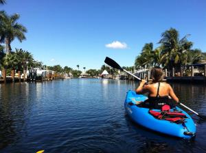 une femme monte un kayak dans l'eau dans l'établissement New! Waterfront Heated Pool & Jacuzzi 2 mi to Beach - Fishing Pier Relaxing SPA & Hammock, à Fort Lauderdale