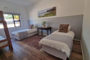 a bedroom with two beds and a table and a window at Bestuis Cottage - Self catering accommodation on a farm in Klapmuts