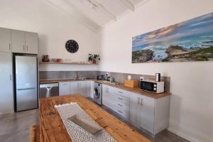 une cuisine avec des armoires blanches et une table en bois dans l'établissement Bestuis Cottages - Die Walvis, à Klapmuts 6 autres photos