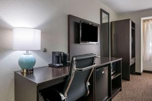 a hotel room with a desk with a lamp and a chair at Sleep Inn Jacksonville Airport in Jacksonville