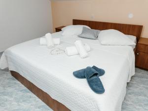 Una cama con toallas y un par de zapatos. en Apartmani Dragobratović, en Komarna