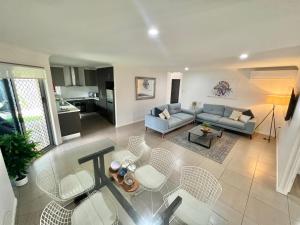 een woonkamer met een bank en een tafel en stoelen bij Bundys Best! Modern Luxury in the heart of town in Bundaberg