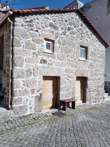 a stone building with two doors and a bench in front at Casa da Porta velha in São Gião