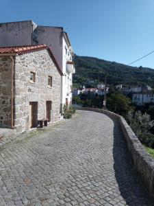 a cobblestone street next to a stone building at Casa da Porta velha in São Gião