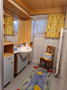 a bathroom with a sink and a shower and a chair at Haus Frei-Nagele in Alpbach